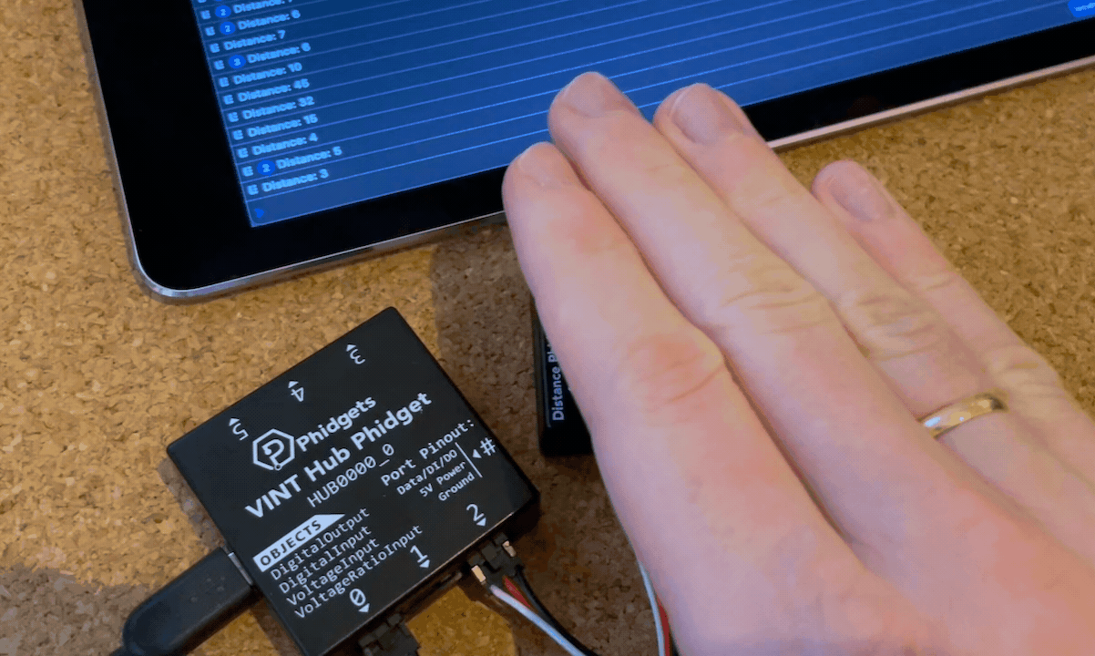 Hand moving closer and further away from the distance sensor showing the distance in the console output