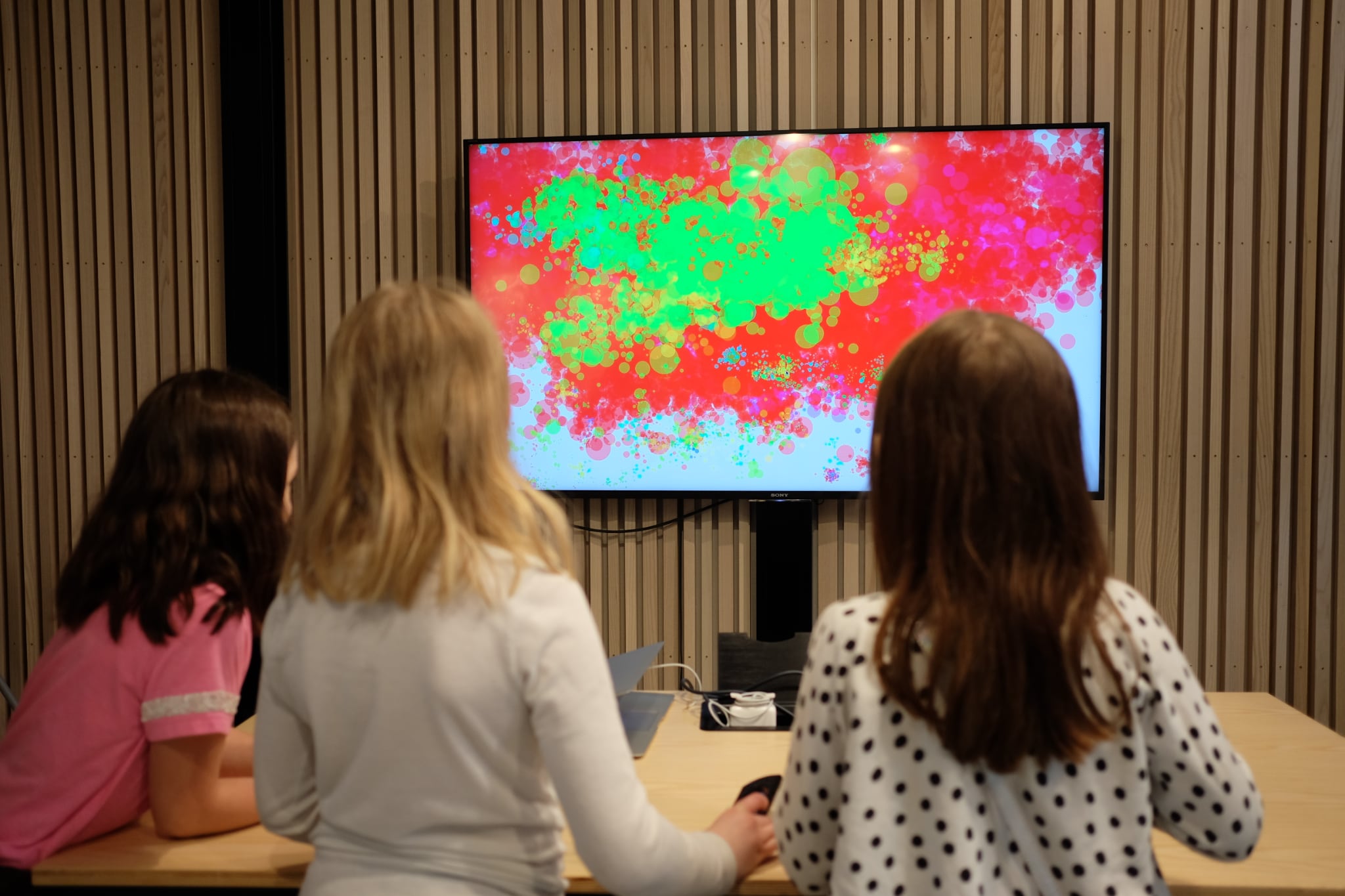 Kids standing in front of a screen with splashes of in color